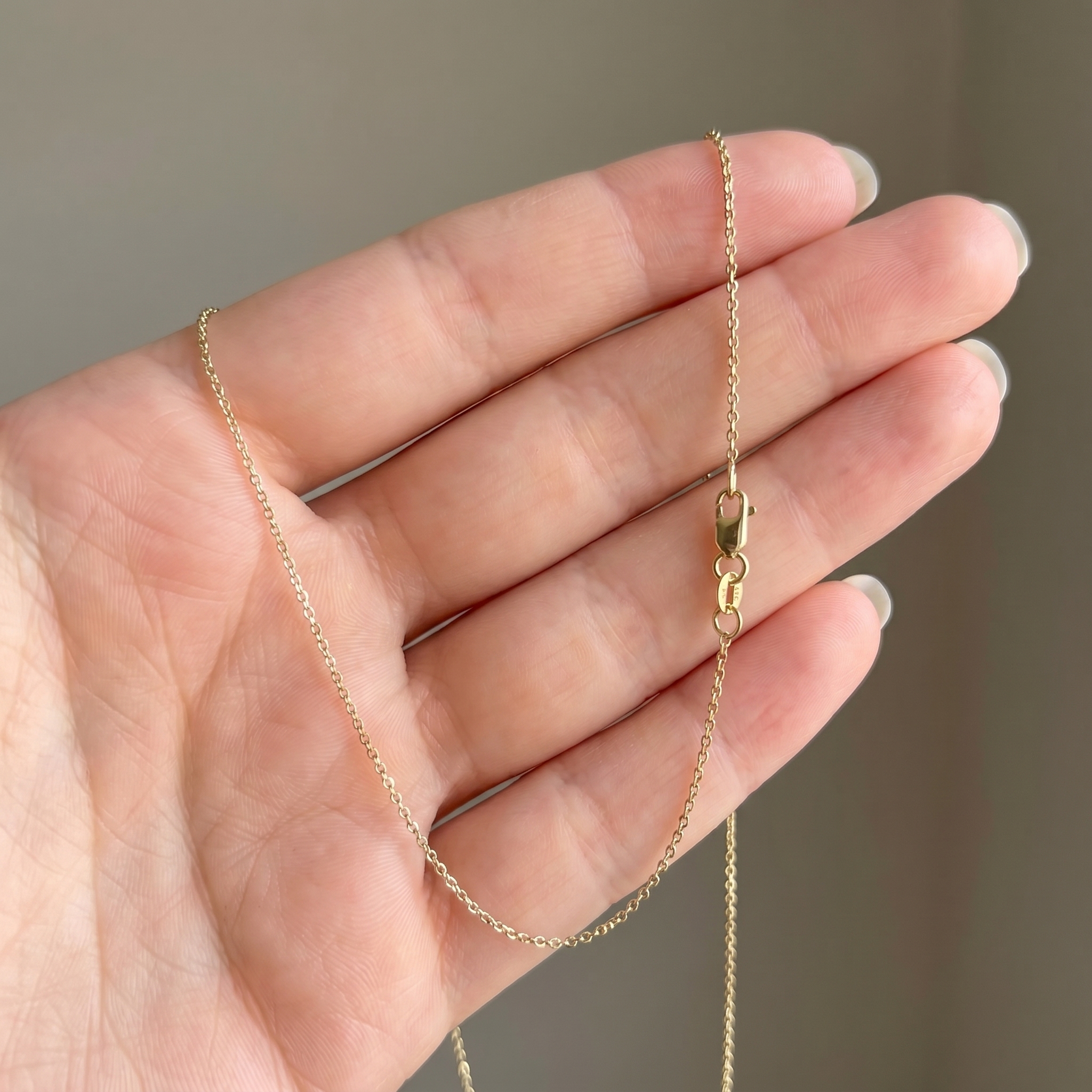 AI-generated lifestyle shot of a delicate gold chain held in hand