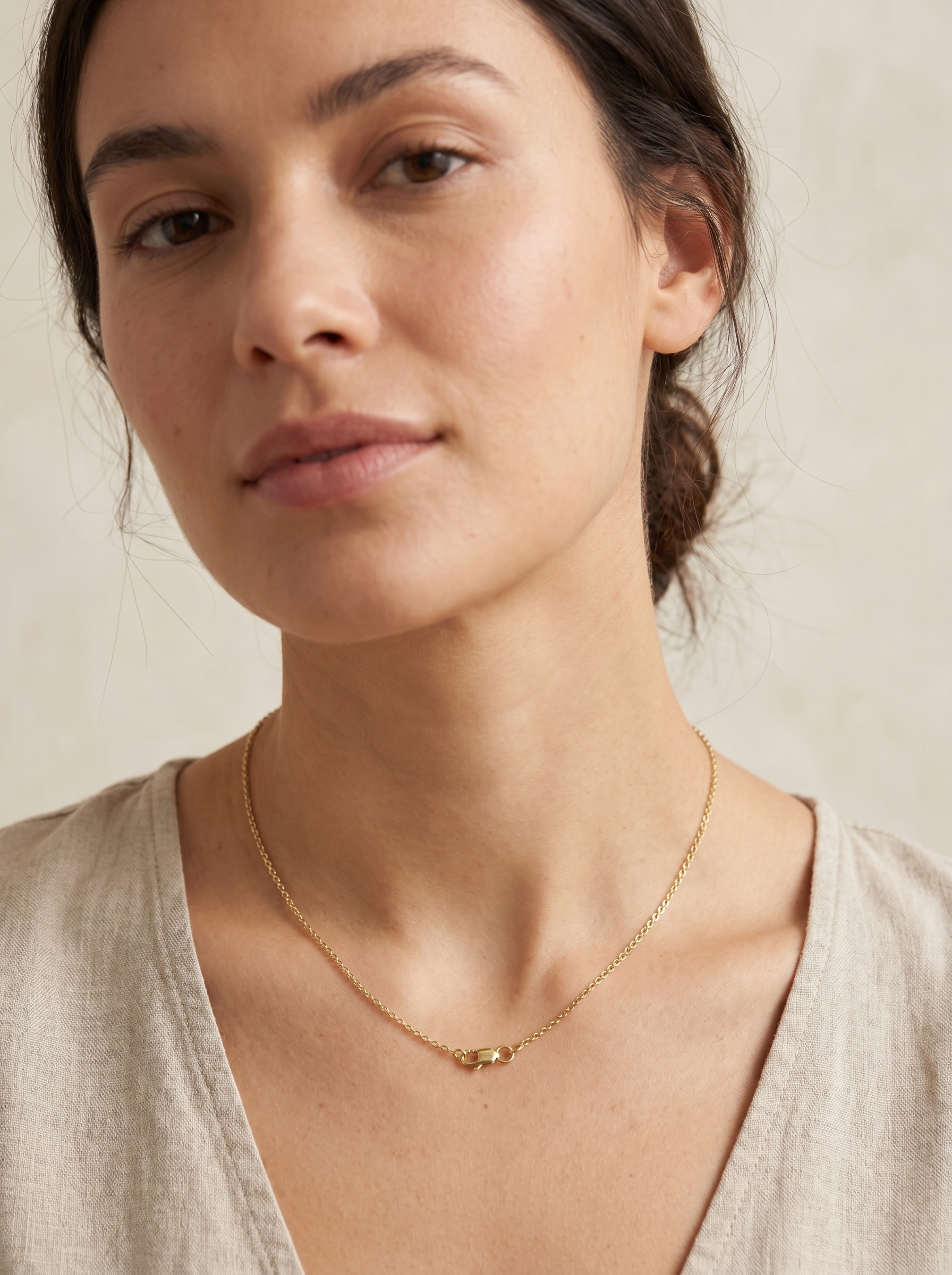 AI-generated model shot of a woman wearing a thin gold chain necklace